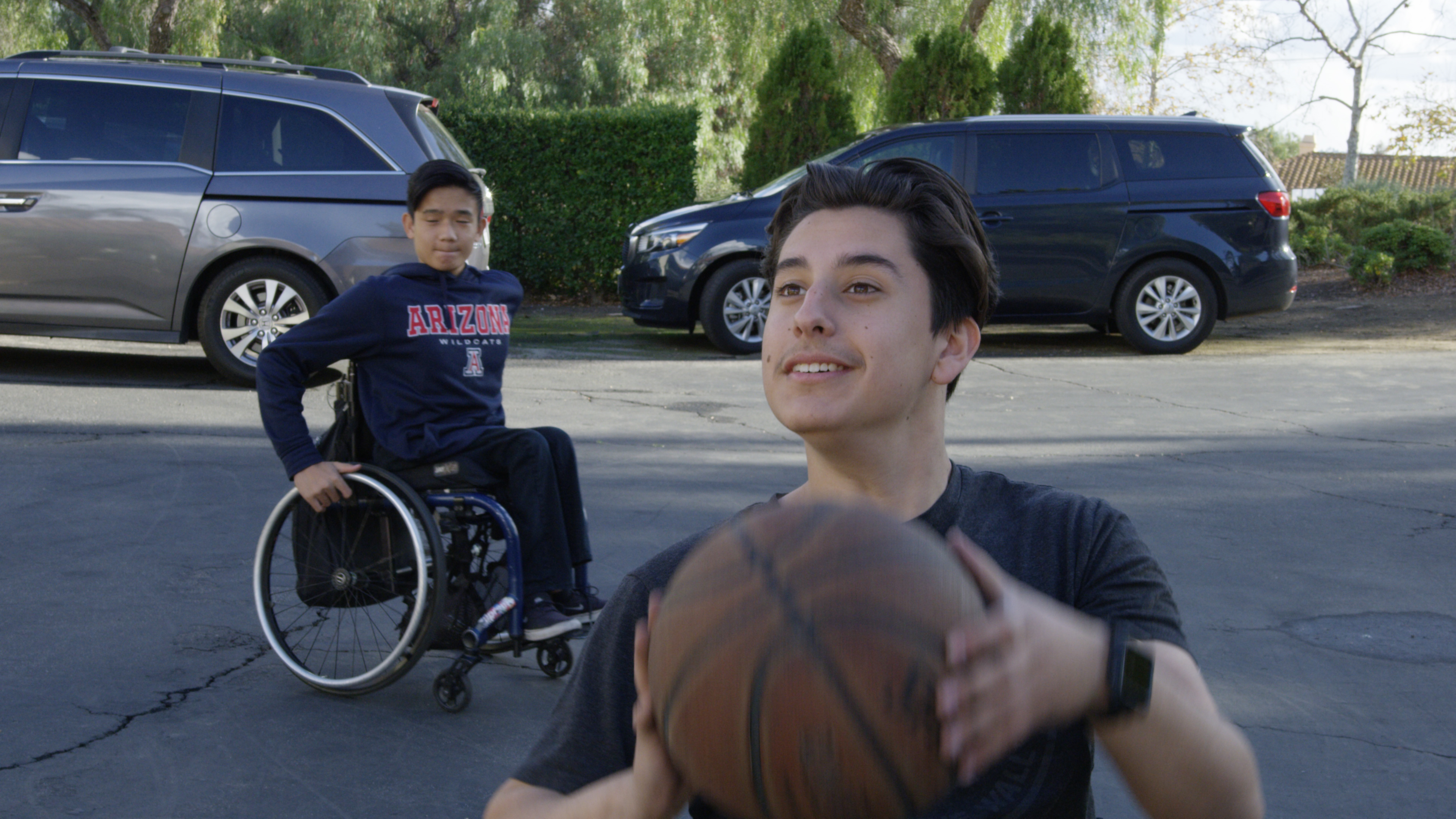 Danny practicing wheel chair basketball with a friend.