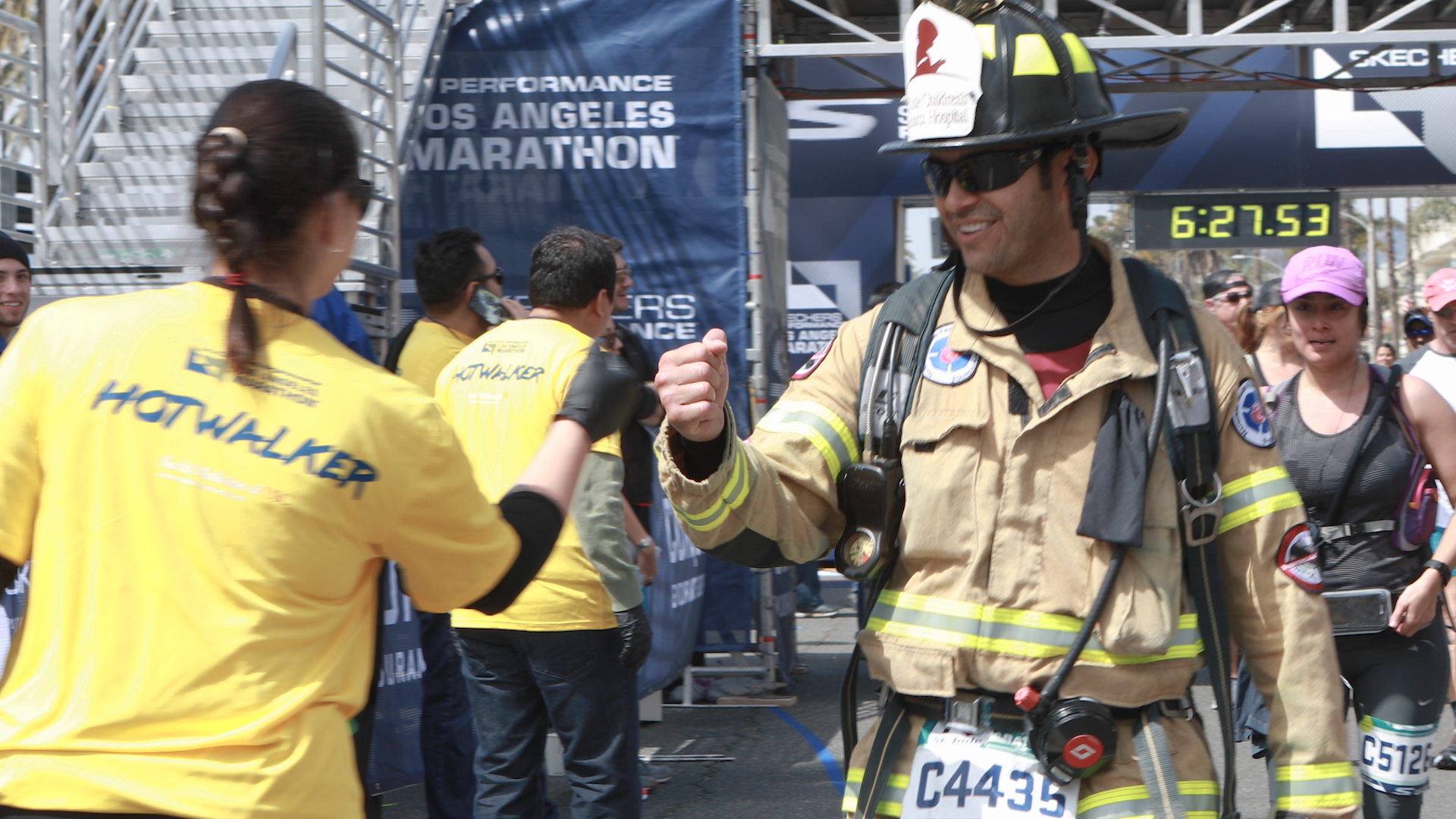 Jose Zambrano giving a fist pump to a fan at the finish line of a marathon.